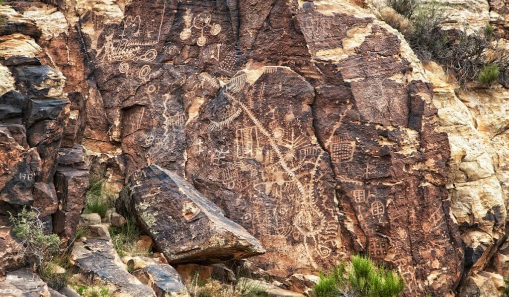 Petroglyphs carved into a rocky surface, depicting abstract shapes and symbols.